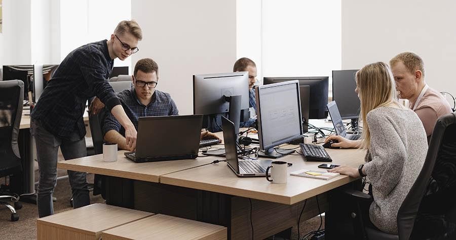 pessoas reunidas trabalahdno em uma empresa, ambiente em que podem ocorrer ataques virtuais